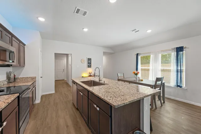 a kitchen with granite countertop kitchen island a sink stove and wooden floor