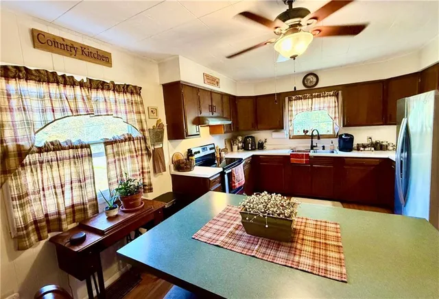 a kitchen with a refrigerator a stove a sink dishwasher a dining table and chairs with wooden floor