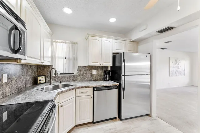 a kitchen with a refrigerator sink and cabinets