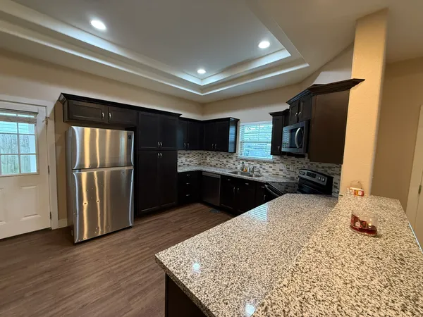 a kitchen with stainless steel appliances kitchen island granite countertop a refrigerator and a sink