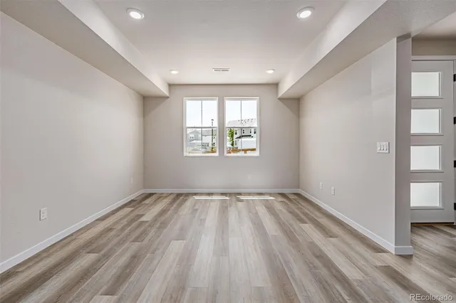 an empty room with wooden floor and windows