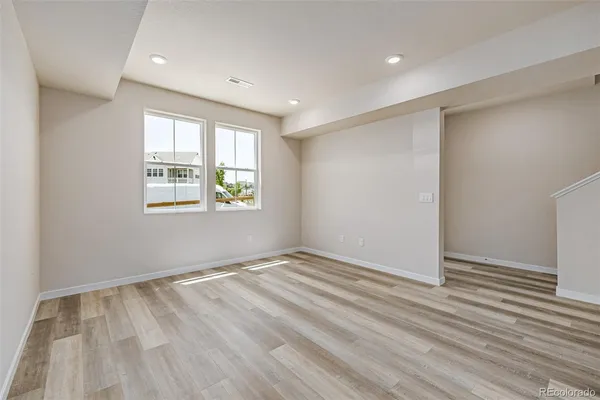 an empty room with wooden floor and windows