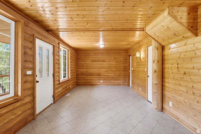 2640 East Weber Canyon Road Oakley, UT 84055 - Photo 19 of 56 Wood-paneled walls and ceiling, white paneled doors, square tile flooring, and multiple windows