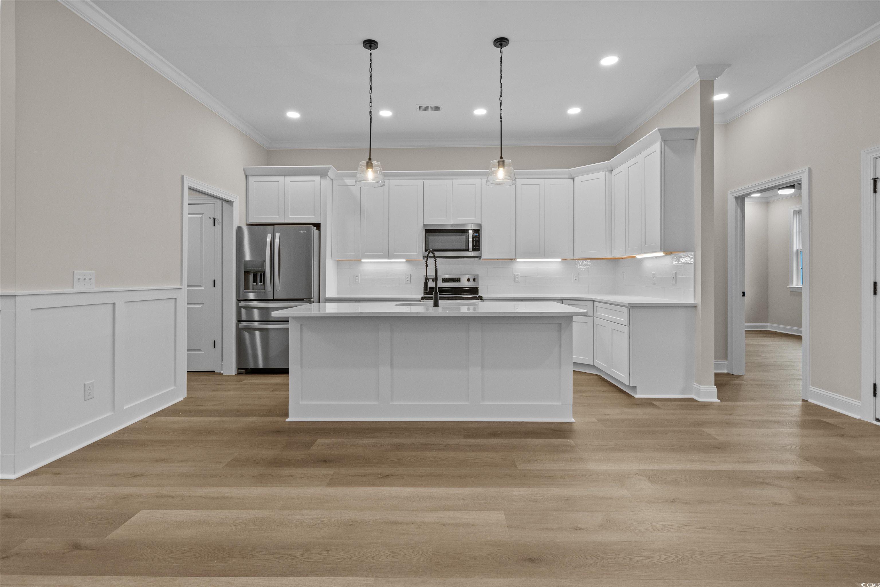 6927 Pauley Swamp Road Conway, SC 29527 - Photo 13 of 40 Kitchen with white cabinets, appliances with stainless steel finishes, pendant lighting, recessed lighting, and a kitchen island with sink