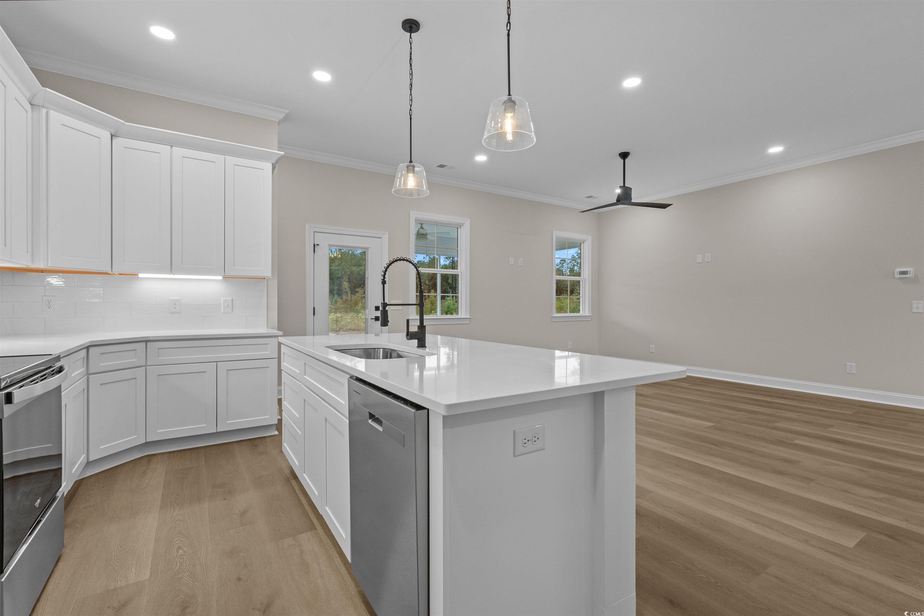 6927 Pauley Swamp Road Conway, SC 29527 - Photo 14 of 40 Kitchen with white cabinets, ornamental molding, light wood-style floors, backsplash, and stainless steel appliances