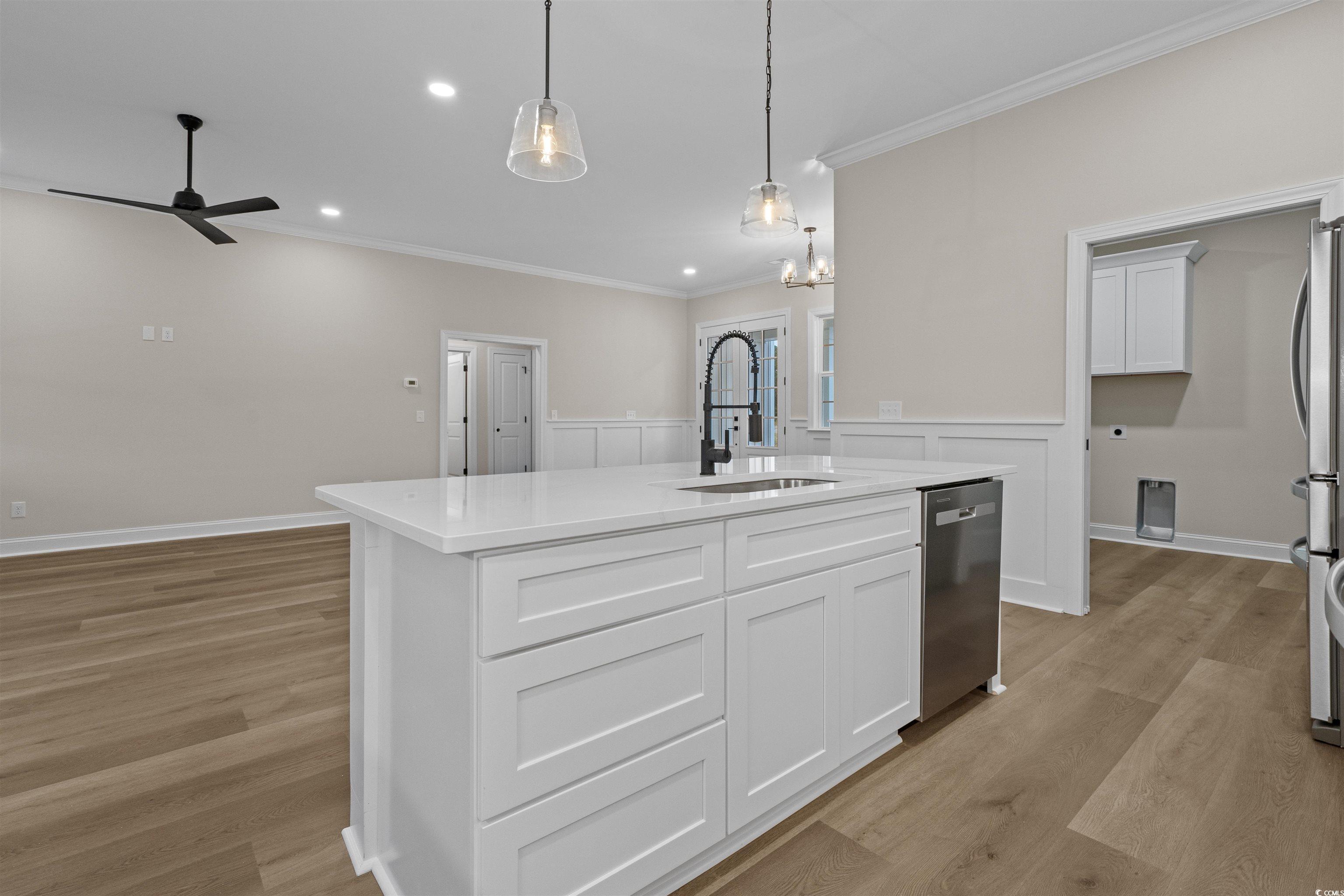 6927 Pauley Swamp Road Conway, SC 29527 - Photo 16 of 40 Kitchen with a kitchen island with sink, white cabinets, ornamental molding, decorative light fixtures, and light wood finished floors