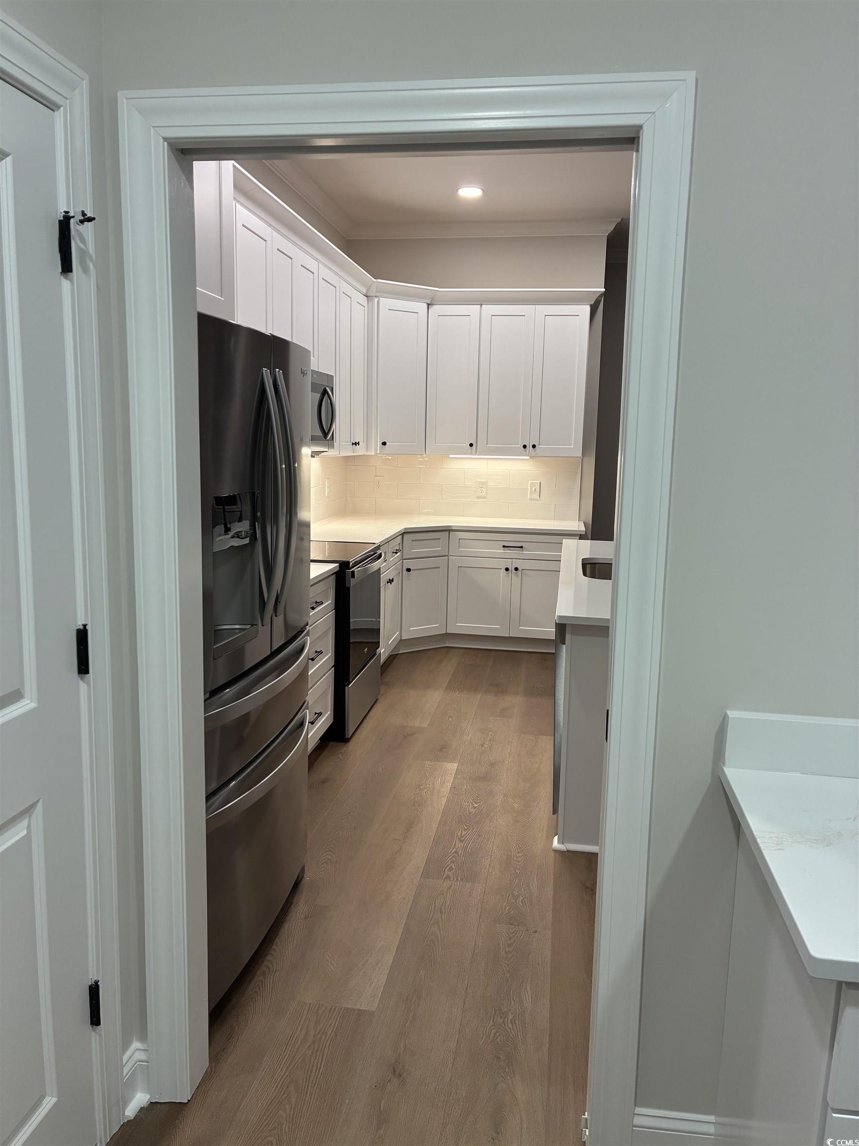 6927 Pauley Swamp Road Conway, SC 29527 - Photo 18 of 40 Kitchen featuring white cabinets, dark wood-style floors, appliances with stainless steel finishes, decorative backsplash, and light stone countertops