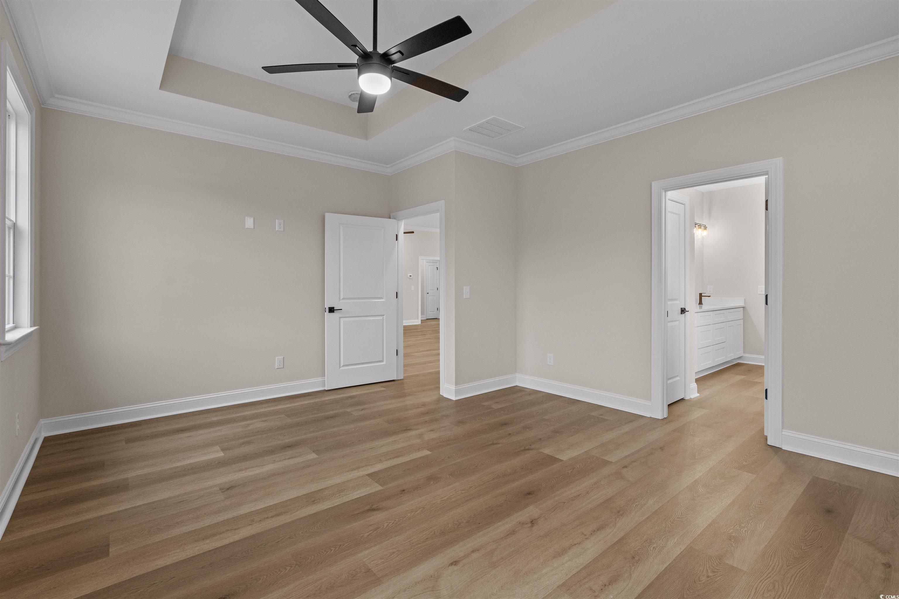 6927 Pauley Swamp Road Conway, SC 29527 - Photo 27 of 40 Unfurnished bedroom with a raised ceiling, ornamental molding, light wood-type flooring, a ceiling fan, and connected bathroom