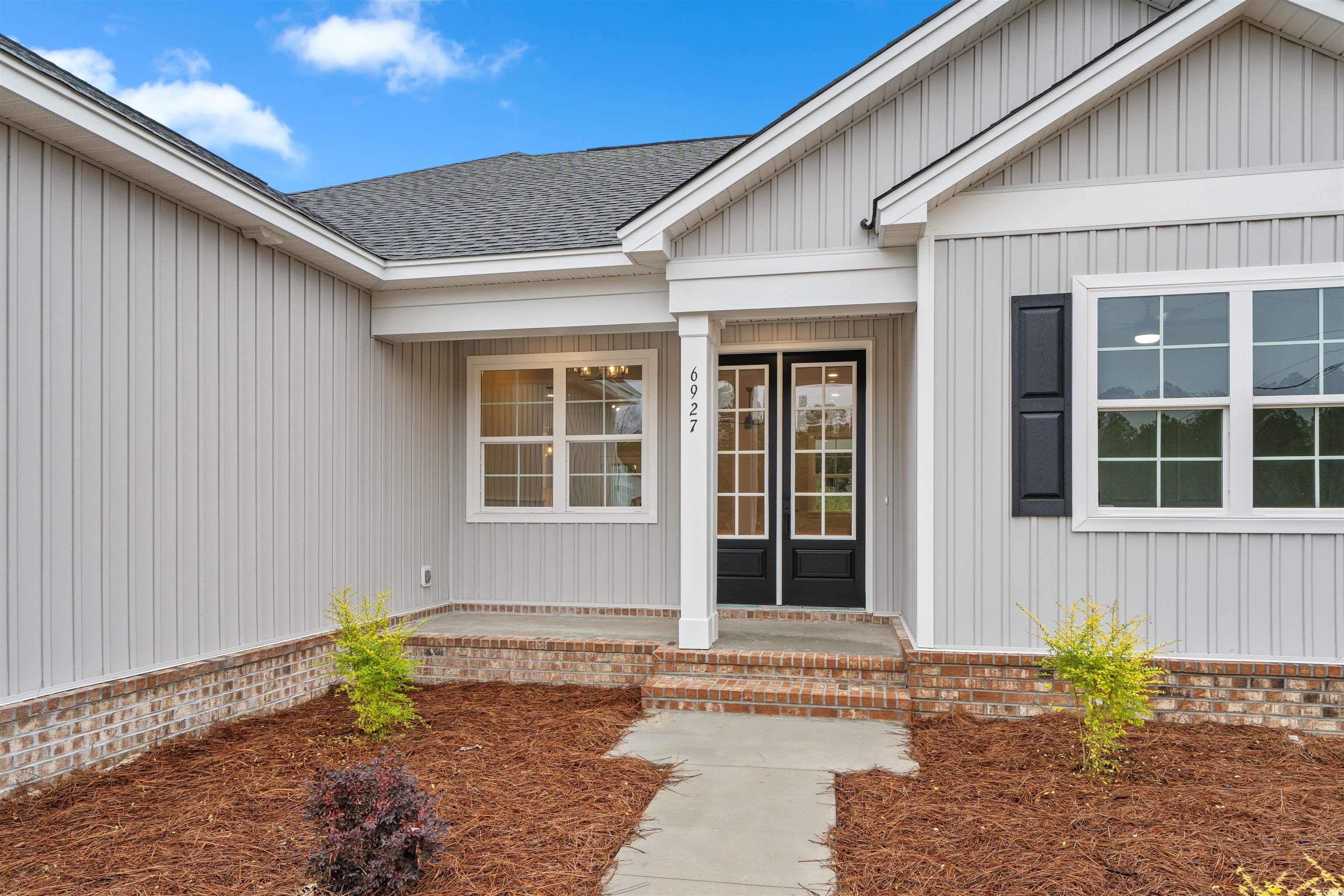 6927 Pauley Swamp Road Conway, SC 29527 - Photo 3 of 40 Doorway to property with a porch, roof with shingles, and board and batten siding