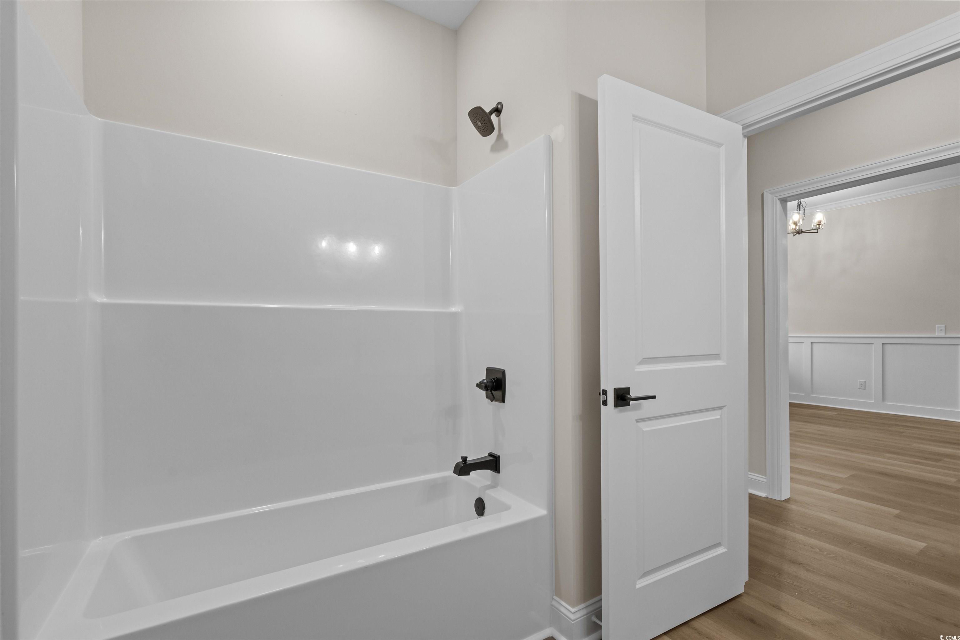 6927 Pauley Swamp Road Conway, SC 29527 - Photo 38 of 40 Bathroom featuring bathtub / shower combination, wood finished floors, wainscoting, a chandelier, and a decorative wall