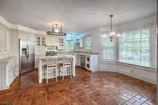 a kitchen with stainless steel appliances a dining table chairs a sink and cabinets