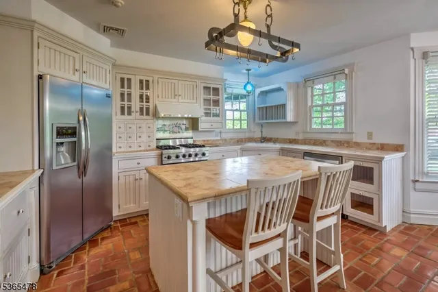 a kitchen with stainless steel appliances granite countertop a kitchen island hardwood floor and a window