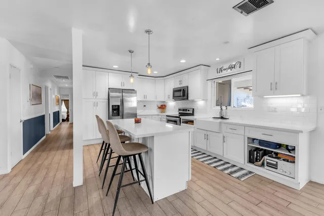 a large white kitchen with a stove a sink dishwasher and a refrigerator with wooden floor