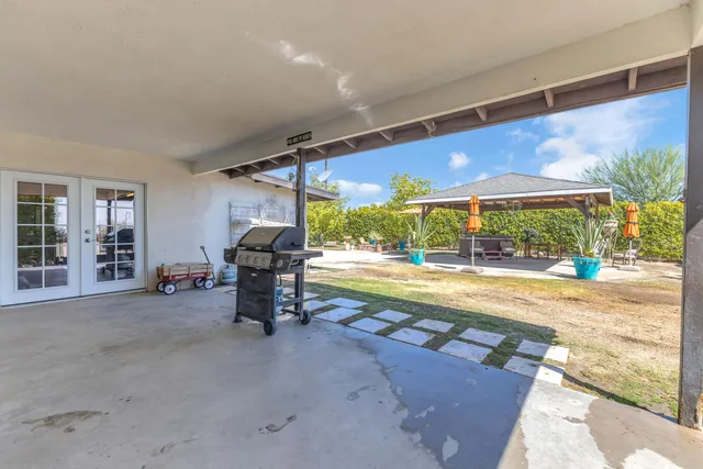 a view of a patio with table and chairs under an umbrella with a big yard