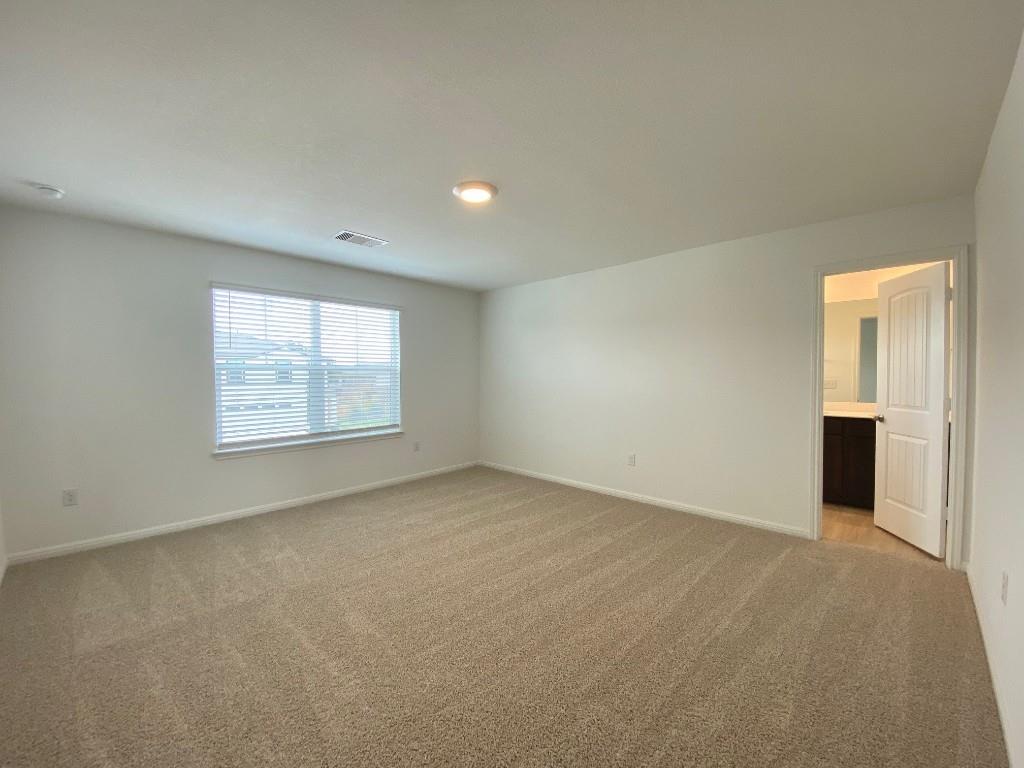 100 Calla Lane Georgetown, TX 78626 - Photo 7 of 8 A spacious room featuring comfortable carpeting, a well-lit ceiling fixture, and convenient access to an adjoining bathroom.
