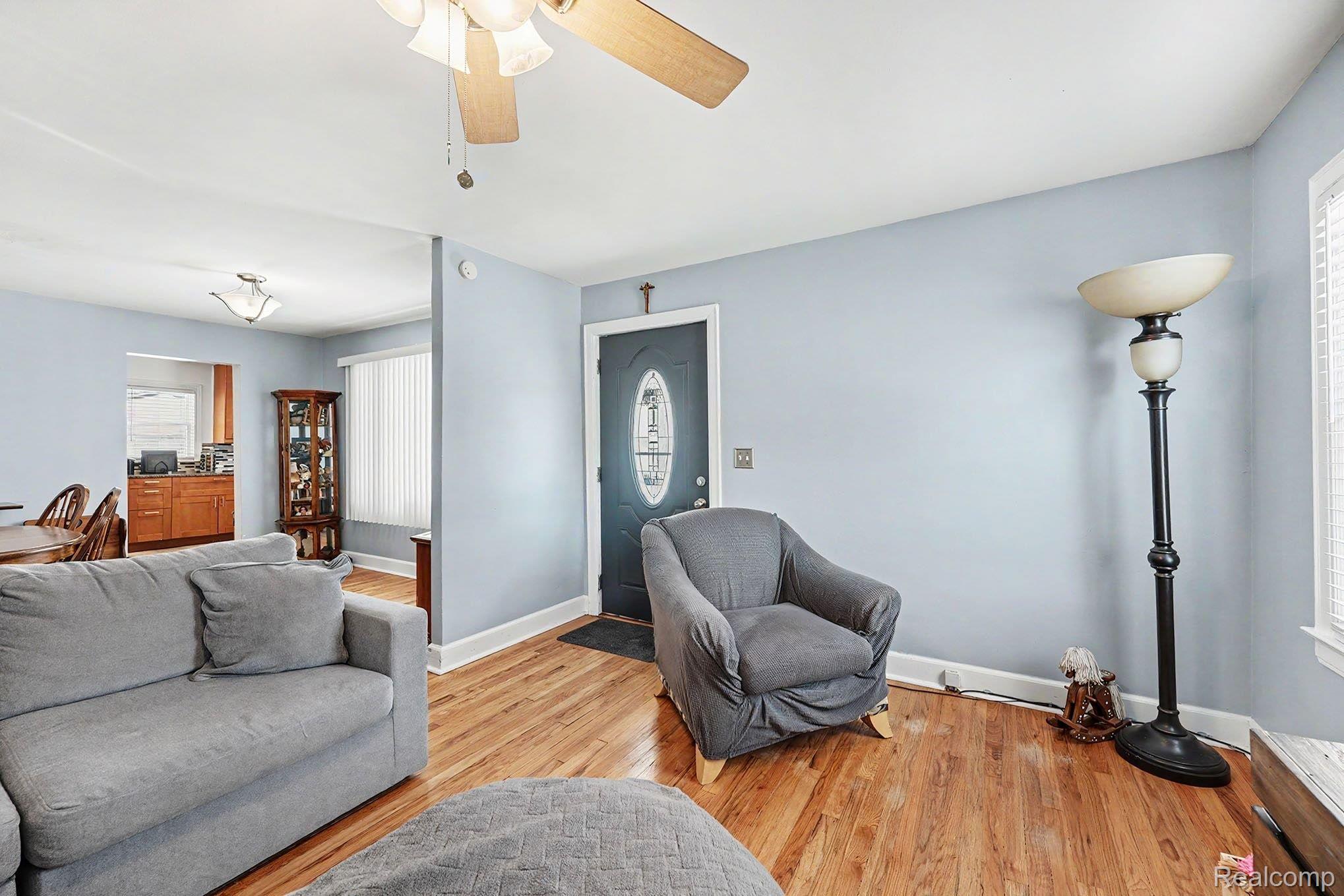 8215 Clinton River Road Sterling Heights, MI 48314 - Photo 6 of 28 Living area featuring wood-finish flooring, a ceiling fan with integrated lighting, and light blue wall finishes