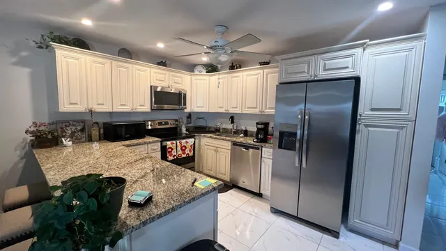 a kitchen with stainless steel appliances granite countertop a refrigerator a stove a sink and a microwave