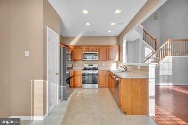 a large kitchen with stainless steel appliances kitchen island granite countertop a large counter top and a view of living room