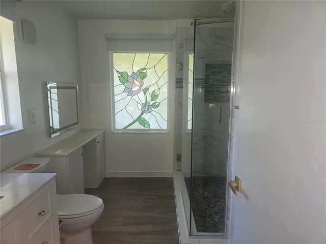 a bathroom with a granite countertop toilet a sink and a shower