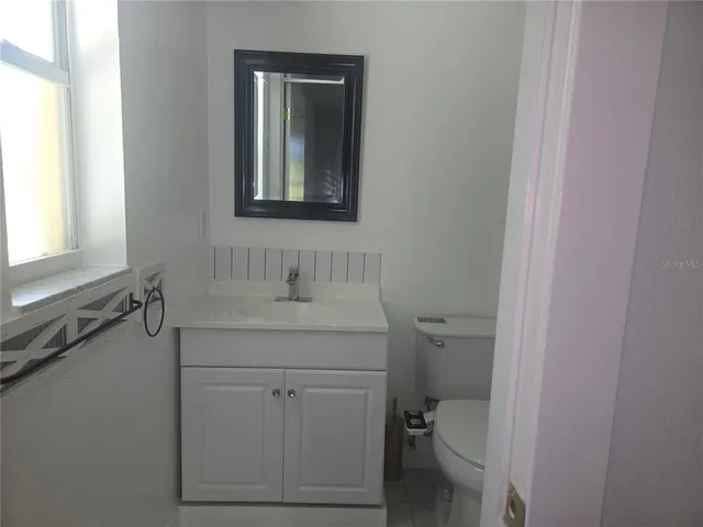 a bathroom with a granite countertop toilet sink and mirror