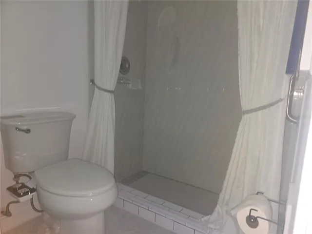 a white toilet sitting next to a shower