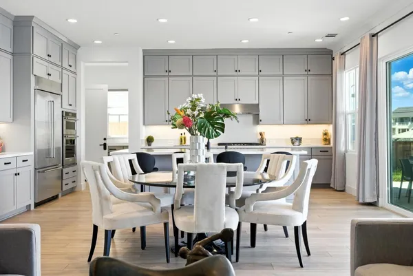 a kitchen with stainless steel appliances granite countertop a table chairs sink refrigerator and cabinets