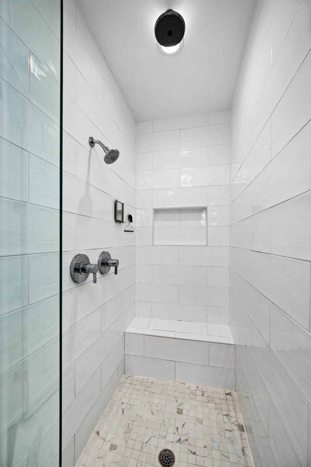 1103 Saucedo Street, Unit 1 Austin, TX 78721 - Photo 32 of 40 A well-appointed shower offers both a traditional showerhead and a ceiling-mounted rainfall fixture, complete with built-in bench seating.