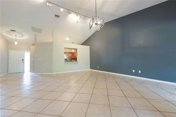 a view of an empty room and a chandelier fan