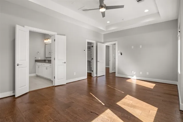 an empty room with wooden floor and ceiling fan