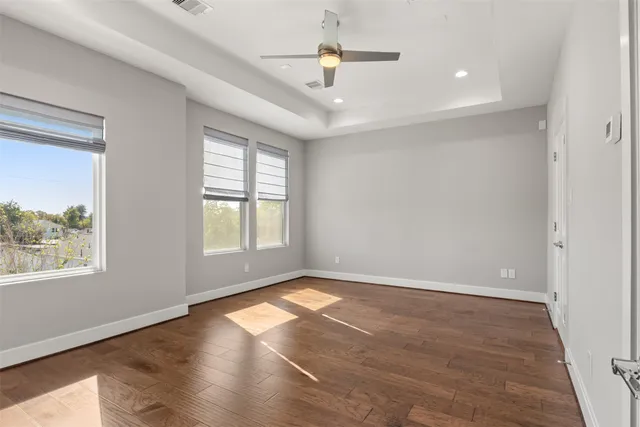 an empty room with wooden floor and windows