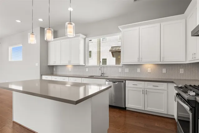 a kitchen with kitchen island granite countertop a sink a stove and cabinets