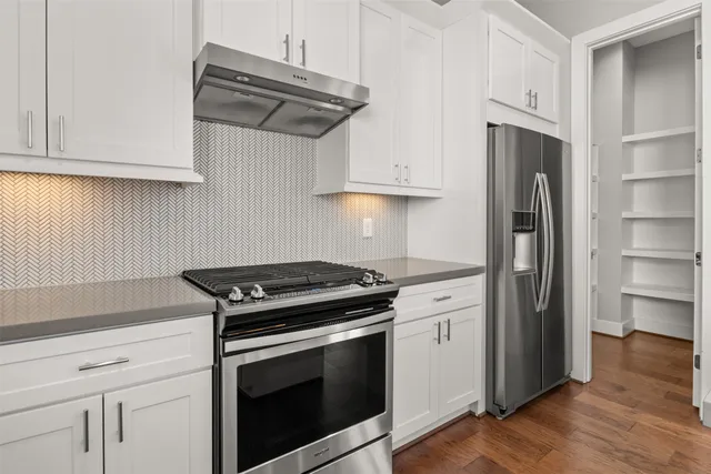 a kitchen with stainless steel appliances white cabinets and a stove top oven