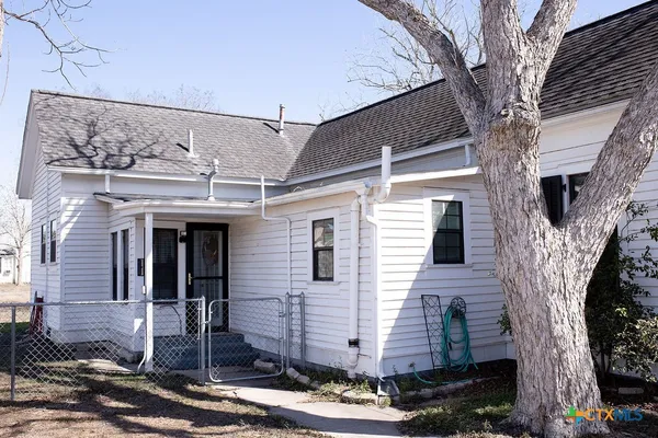 a tree in front of a house with a yard