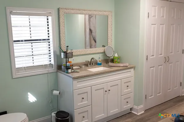 a bathroom with a granite countertop sink a toilet and a mirror