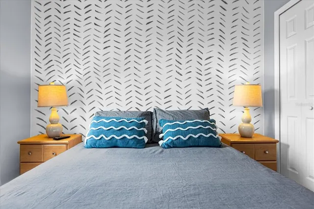 a bedroom with a bed and a lamp on dresser