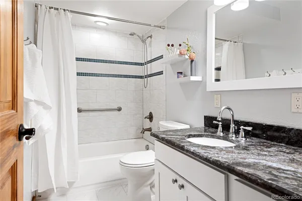 a bathroom with a granite countertop sink a toilet and shower