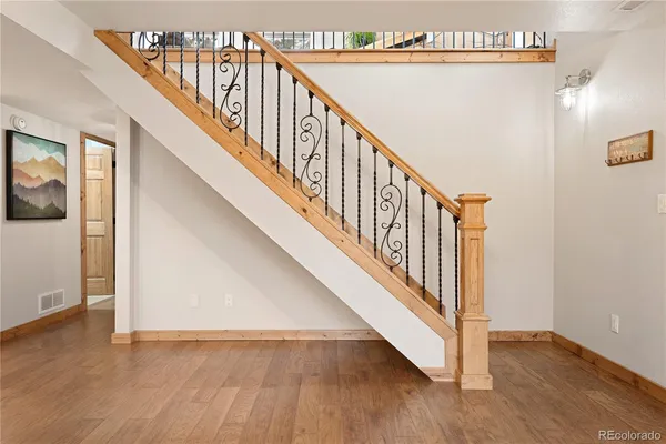 a view of a hallway with wooden floor and stairs