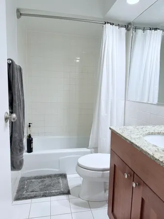 a bathroom with a granite countertop bathtub shower and toilet