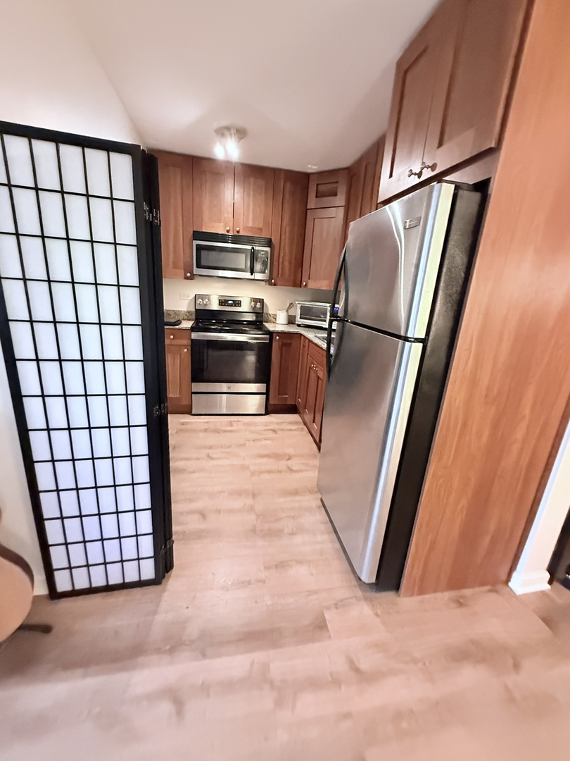 3033 North Sheridan Road, Unit 809 Chicago, IL 60657 - Photo 8 of 20 a kitchen with stainless steel appliances a refrigerator and a stove top oven