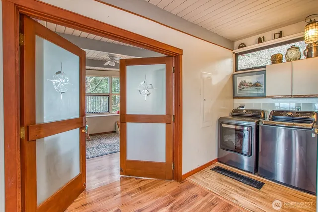 a view of a refrigerator in kitchen and an empty room with wooden floor