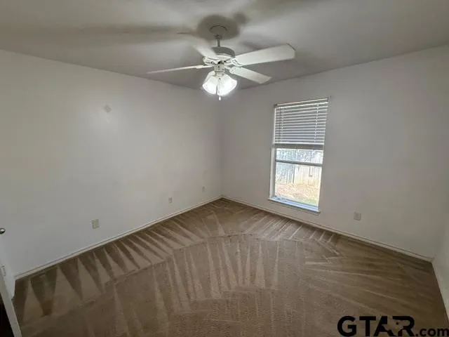 an empty room with a window and a ceiling fan
