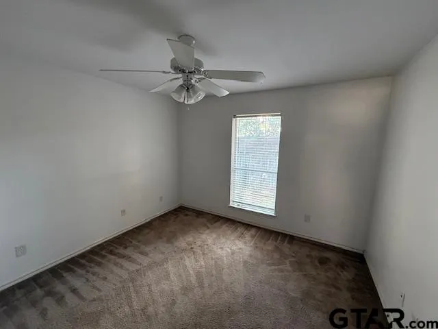 an empty room with a window and a fan