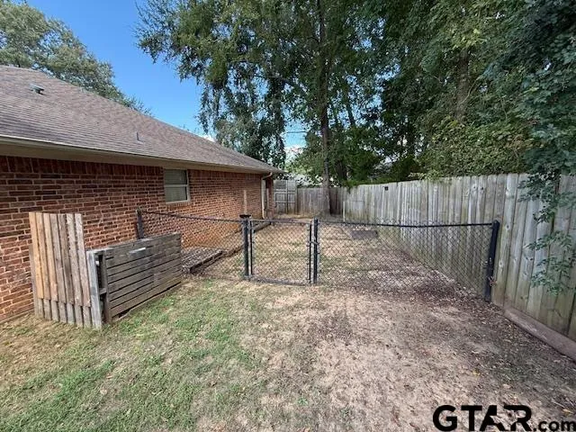 a view of backyard with wooden fence and large trees