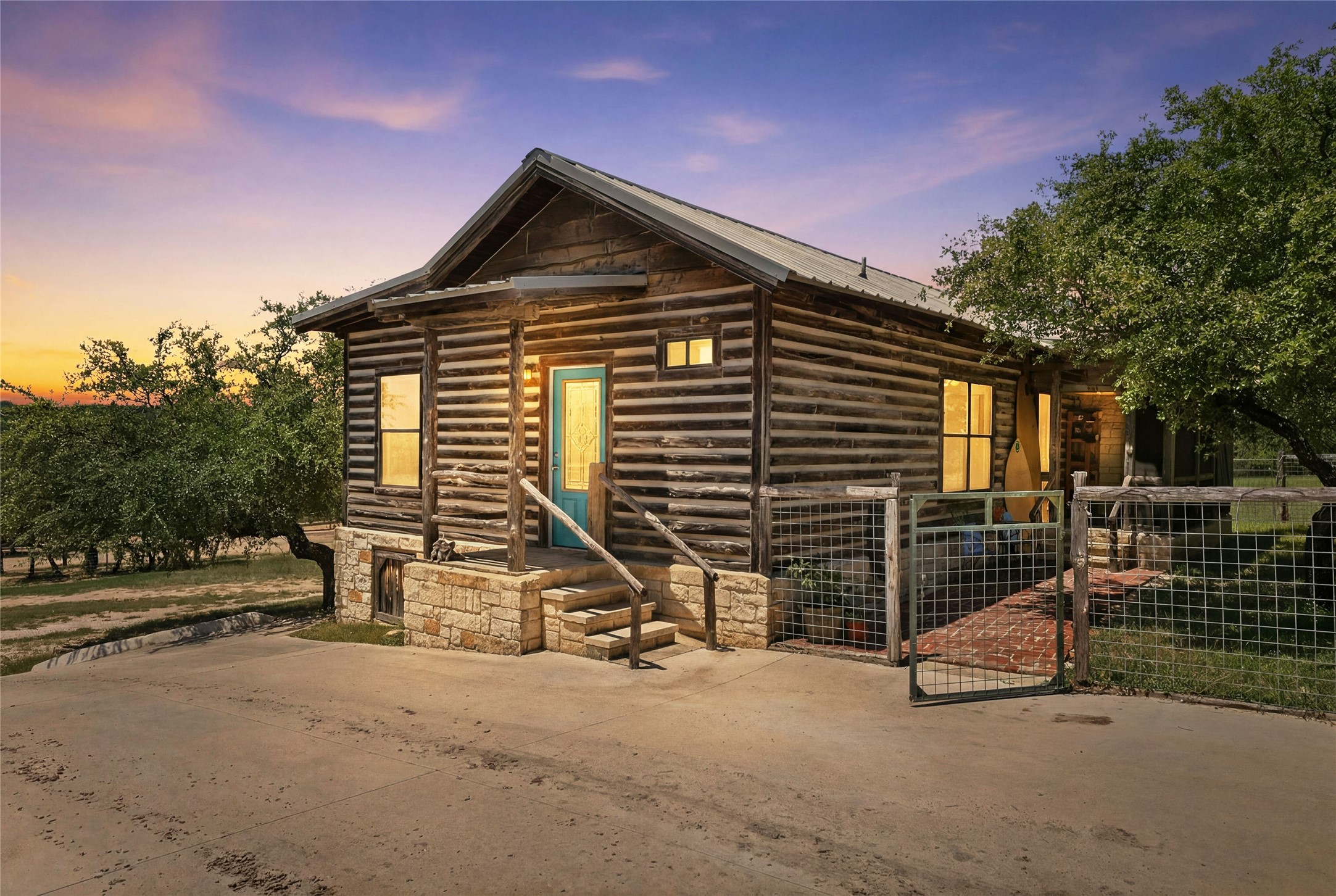 496 Middleton Road Spicewood, TX 78669 - Photo 1 of 40 Rustic log cabin exterior with a metal roof and stone foundation