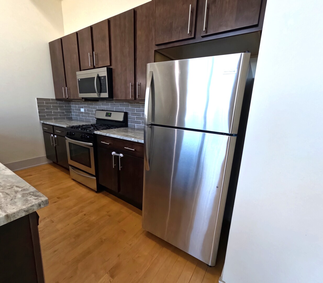 1432 West 21st Street, Unit 321 Chicago, IL 60608 - Photo 11 of 25 a kitchen with stainless steel appliances granite countertop a refrigerator a stove a sink and a microwave