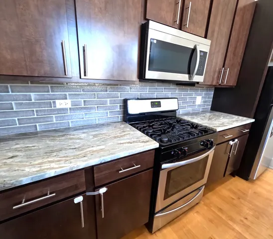 a kitchen with granite countertop a stove top oven cabinetry a sink and a microwave