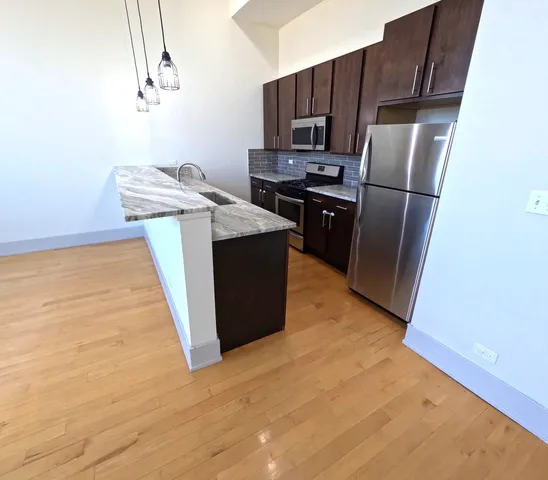 a kitchen with stainless steel appliances a refrigerator and a wooden floor