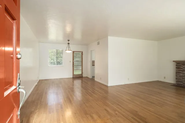 an empty room with wooden floor cabinet and windows