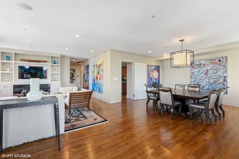 a view of dining room and livingroom with furniture wooden floor a rug a painting and a chandelier