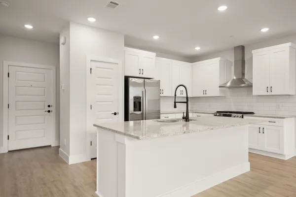 a kitchen with stainless steel appliances granite countertop a sink a stove a refrigerator and cabinets